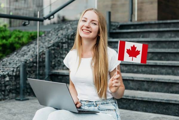 Female Student Sitting Stairs With Laptop Holding Small Canada Flag 600x403